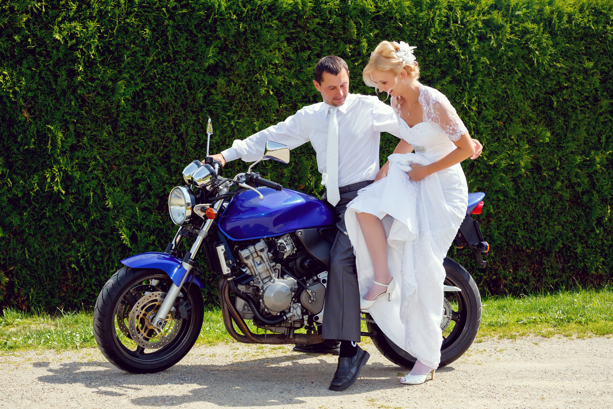 Bride and groom getting on motorcycle on wedding day