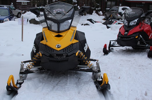 Yellow and black snowmobile front on snow after riding on trails