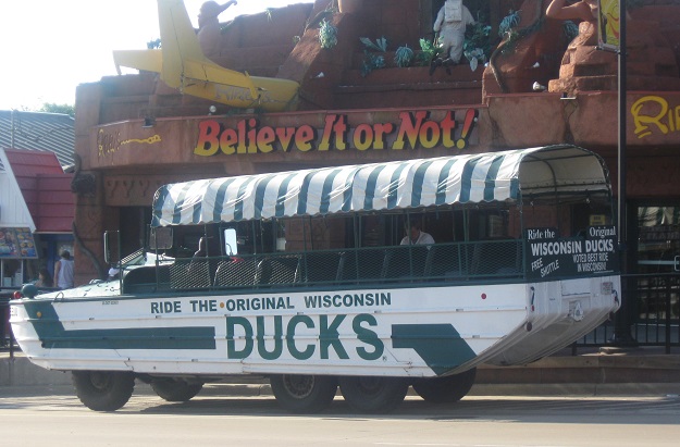 World war II Army DUCK restored and driving on a street in Wisconsin Dells. Painted white with large green lettering.