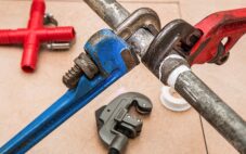 Plumber tools - one blue and one red pipe wrench held by two galvanized pipe sections bound with a connector