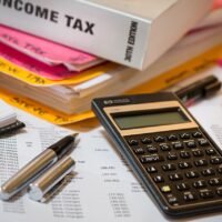 Calculator and income tax book along with a pen and balance sheet